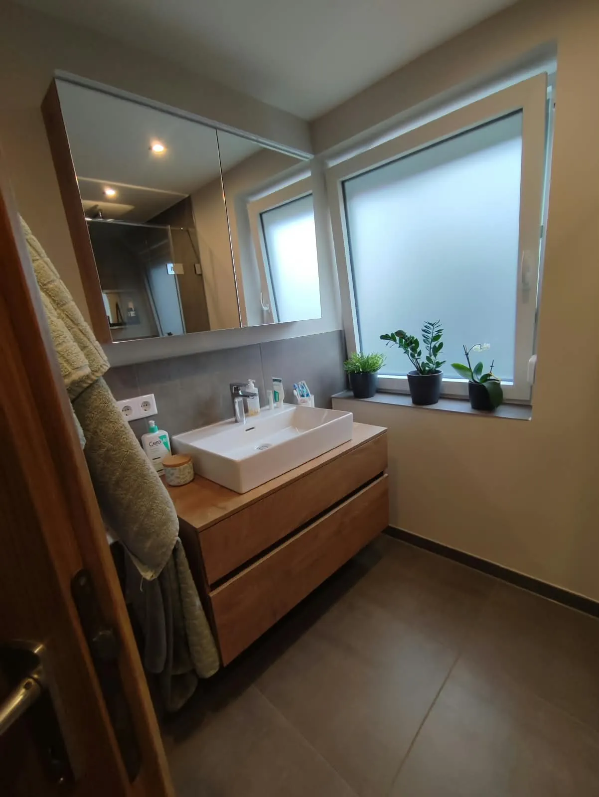 Waschtisch mit Holzunterschrank und Spiegelschrank am Fenster